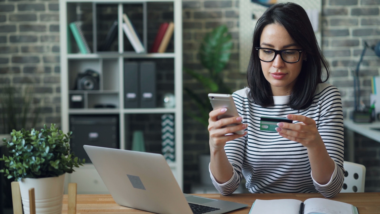 iPhoneとクレジットカードを持ちながら通信プランを比較検討する人物