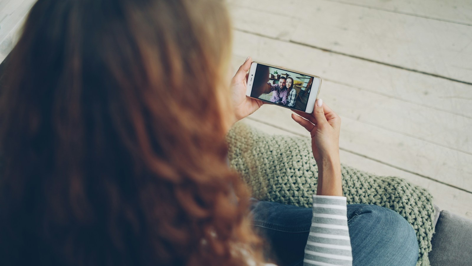 リビングでスマートフォンの動画配信サービスを楽しむ人物